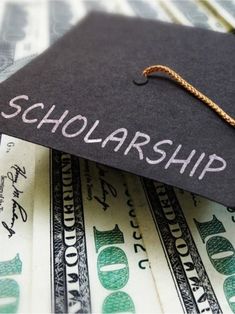 a graduation cap sitting on top of money with the word scholarship written on it's side