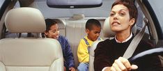 two children are sitting in the back seat of a car and one child is driving