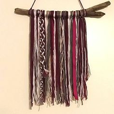 a wall hanging made out of wood and rope with different colored strips on it's sides