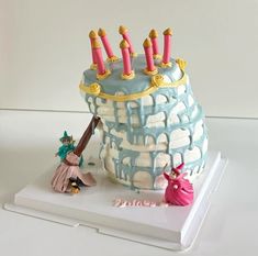 a birthday cake with candles on top of it and a figurine next to it