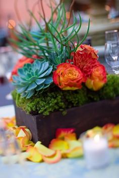 an arrangement of flowers and succulents in a wooden box on a table