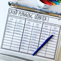 a clipboard with a group planning chart on it next to pens and pencils