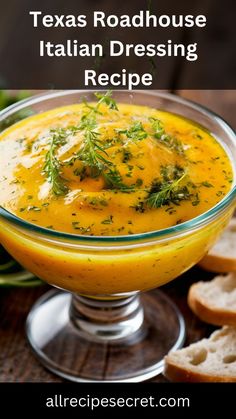 a glass bowl filled with yellow soup and garnished with fresh herbs