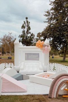 an inflatable bed with balloons and other decorations on the ground at a park