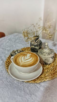 a cappuccino on a wicker tray next to an empty cup and saucer