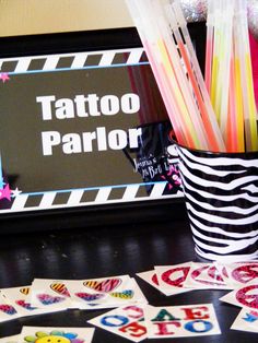 a table topped with lots of tattoos on top of cards and pens in a cup