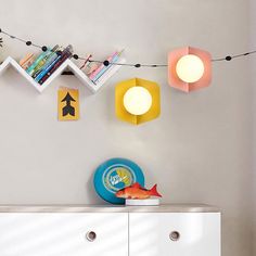 a white dresser topped with lots of drawers and lights hanging from it's sides