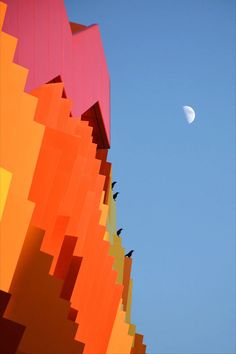 birds are sitting on the top of an art sculpture with a half moon in the background