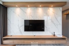 a flat screen tv sitting on top of a wooden shelf in front of a white wall