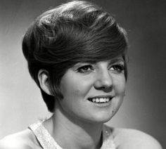 an old black and white photo of a woman with short hair smiling at the camera