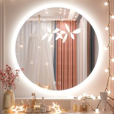 a round mirror with lights around it in front of a white curtain and pink curtains