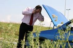 a man standing next to a blue car talking on a cell phone with his head in his hands