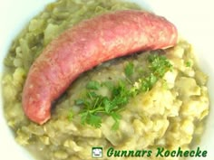 a sausage is on top of mashed potatoes in a white bowl with parsley