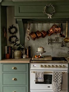 a stove top oven sitting inside of a kitchen next to a wall mounted pot rack