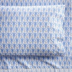 a blue and white bed spread with an elephant pattern on the coverlet, next to a pillow case