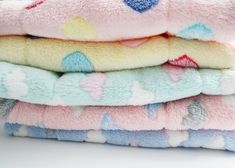 a stack of folded towels on top of each other in pastel colors and hearts