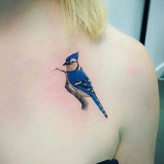 a small blue bird tattoo on the back of a woman's shoulder and chest