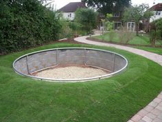 a circular fire pit in the middle of a yard with grass and brick walkways