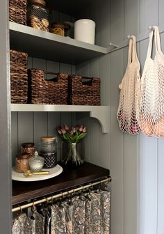 some baskets are hanging on the wall above a shelf in a room with gray walls