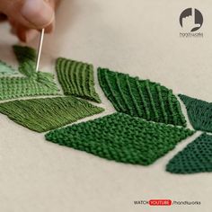 someone is stitching leaves on a piece of fabric