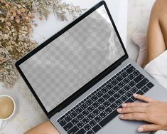 a woman is using her laptop while sitting on the floor with coffee and flowers in front of her