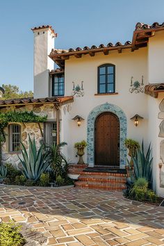 a white house with a brown door and some plants