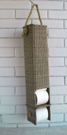 two rolls of toilet paper are hanging from a wicker holder on a brick wall