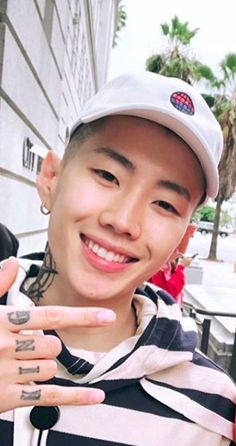 a young man in a striped shirt and cap making the peace sign with his fingers