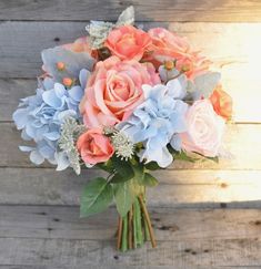 a bouquet of pink roses and blue hydrangeas on a wooden table with planks