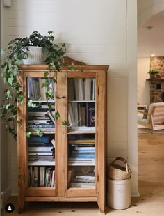 a wooden cabinet with books and plants in it