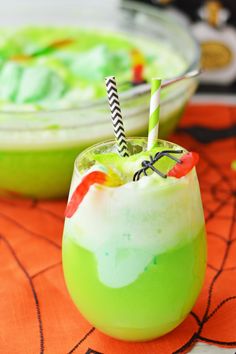 two halloween drinks sitting on top of a table next to each other, one green and the other orange