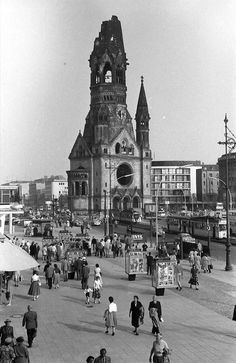 an old black and white photo of people walking in front of a large clock tower