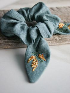 a blue tie with flowers on it sitting next to a piece of wood that is laying on the ground