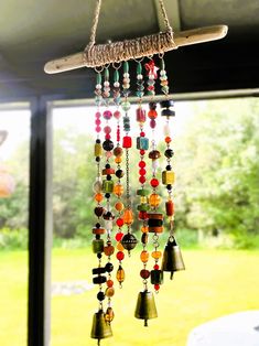 a wind chime hanging from the side of a window with beads and bells attached to it