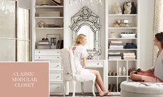 two women are sitting in front of a mirror and dressing table with white furniture on it