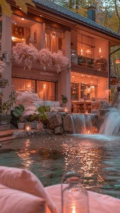 a house with a waterfall in front of it and candles lit on the windows at night