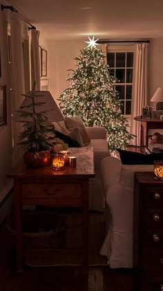 a living room filled with furniture and a lit christmas tree in the corner next to a window