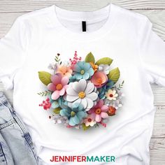 a t - shirt with flowers and leaves on the front, next to denim jeans