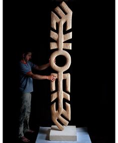 a man standing next to a wooden sculpture