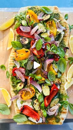 a pizza topped with lots of veggies on top of a wooden cutting board