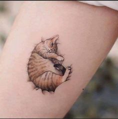 a cat tattoo on the leg of a woman's thigh, with one paw in the air