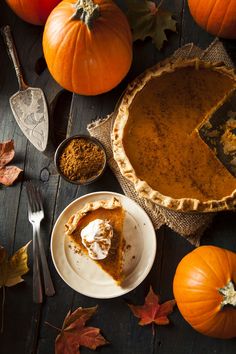 pumpkin pie on a wooden table surrounded by autumn leaves