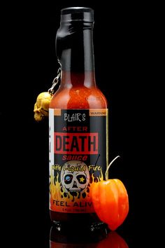 a bottle of hot sauce with a skull on the side and a pepper in front