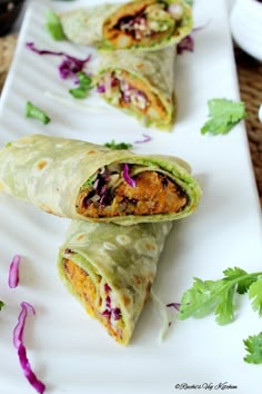 two burritos on a white plate with cilantro garnishes