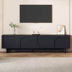 an entertainment center with a flat screen tv mounted on it's sideboard in a living room