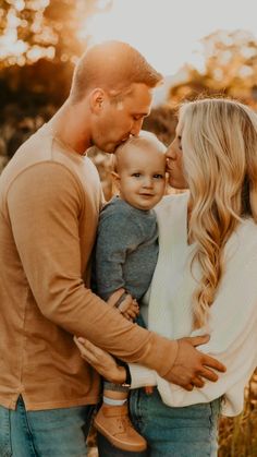 a man and woman holding a baby in their arms while standing next to each other