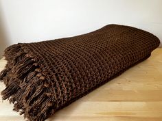 a brown knitted blanket laying on top of a wooden floor