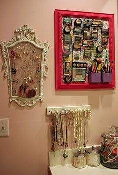 a room with pink walls and pictures on the wall, including jewelry hanging from a red frame