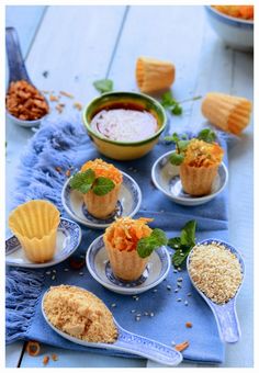 small desserts are arranged on plates with spoons next to them, along with other food items