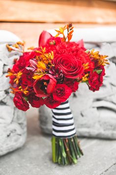 a bouquet of red flowers sitting on top of a table next to a towel and pillows